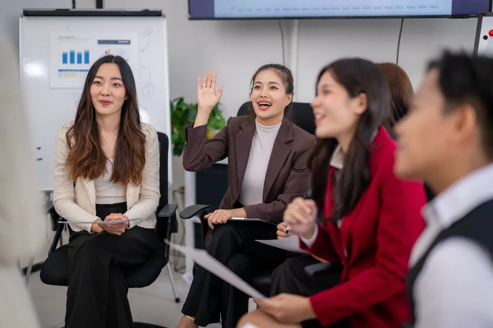 Businesswoman,Raising,Hand,During,A,Meeting,Asking,A,Question,To